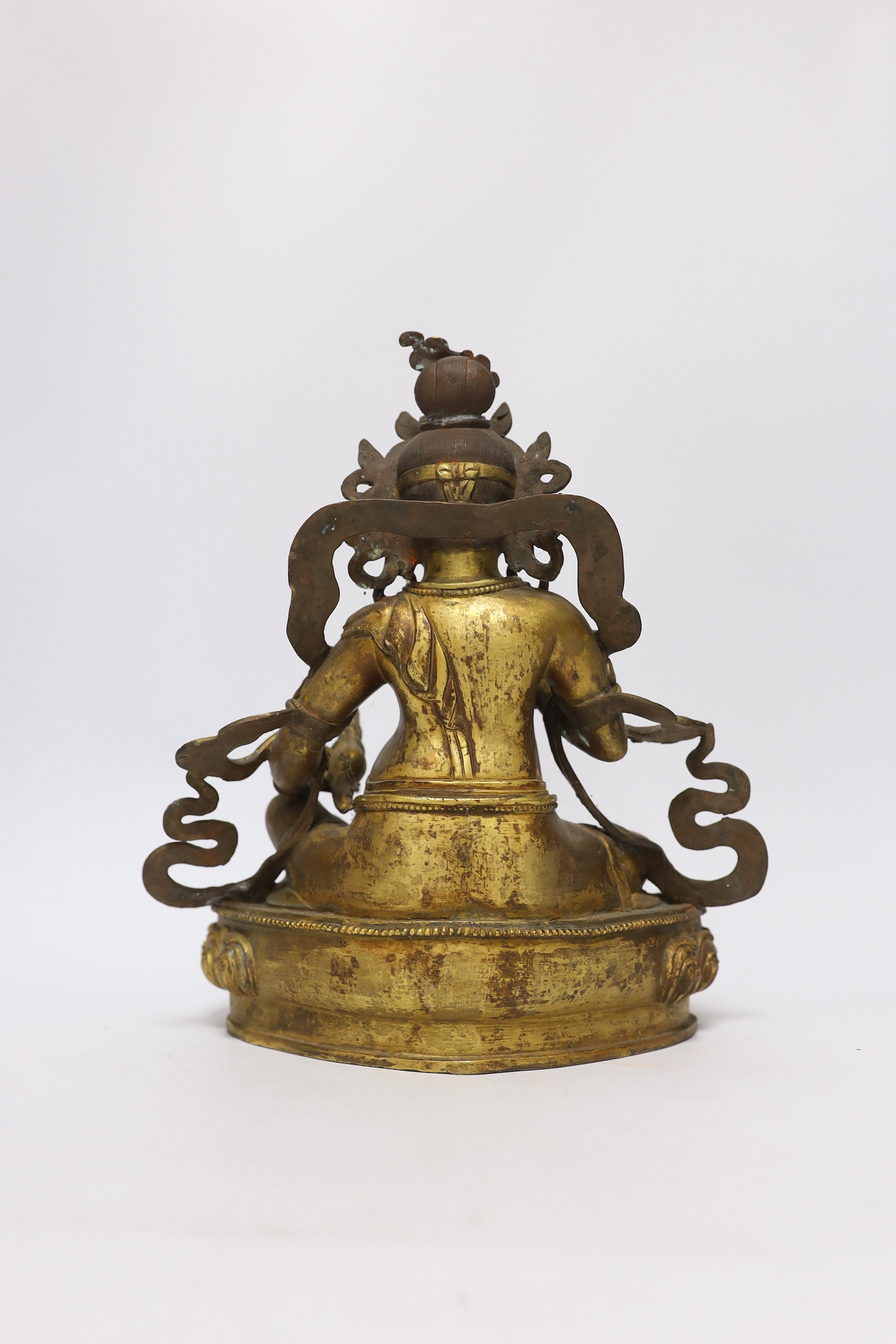 A large Sino-Tibetan gilt bronze seated figure of Jambhala, 28cm high